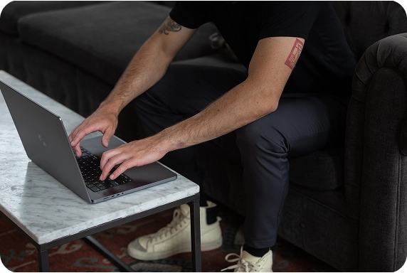 Frau arbeitet mit dem Rücken zugewandt an ihrem Laptop